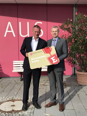 Landrat Dr. Heiko Blume (r.) überreicht dem Geschäftsführer der BBM Gerhard Kreutz symbolisch eine große Ehrenamtskarte