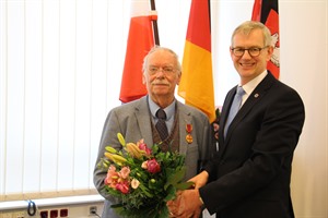 Halwart Schrader (l.) nahm aus den Händen von Landrat Dr. Heiko Blume die Ehrenurkunde und einen üppigen Blumenstrauß entgegen